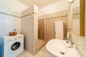 A modern bathroom with a washing machine, a shower enclosure, and a sink. - seasonal rental for 4 people max in large independent garden level (Saint Paul)