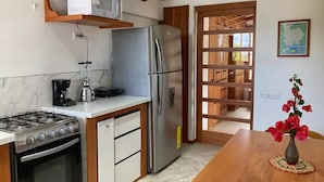 A compact kitchen with a gas stove, microwave, refrigerator, and coffee maker. - GALAPAGOS SUITE VELERO (Puerto Ayora)