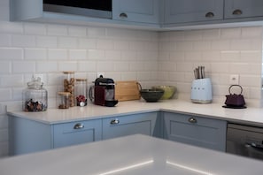 A kitchen with white subway tiles, light blue cabinets, and various kitchen items on the counter. - Vineyard Retreat | Infinity Pool & River Views (Maureles)
