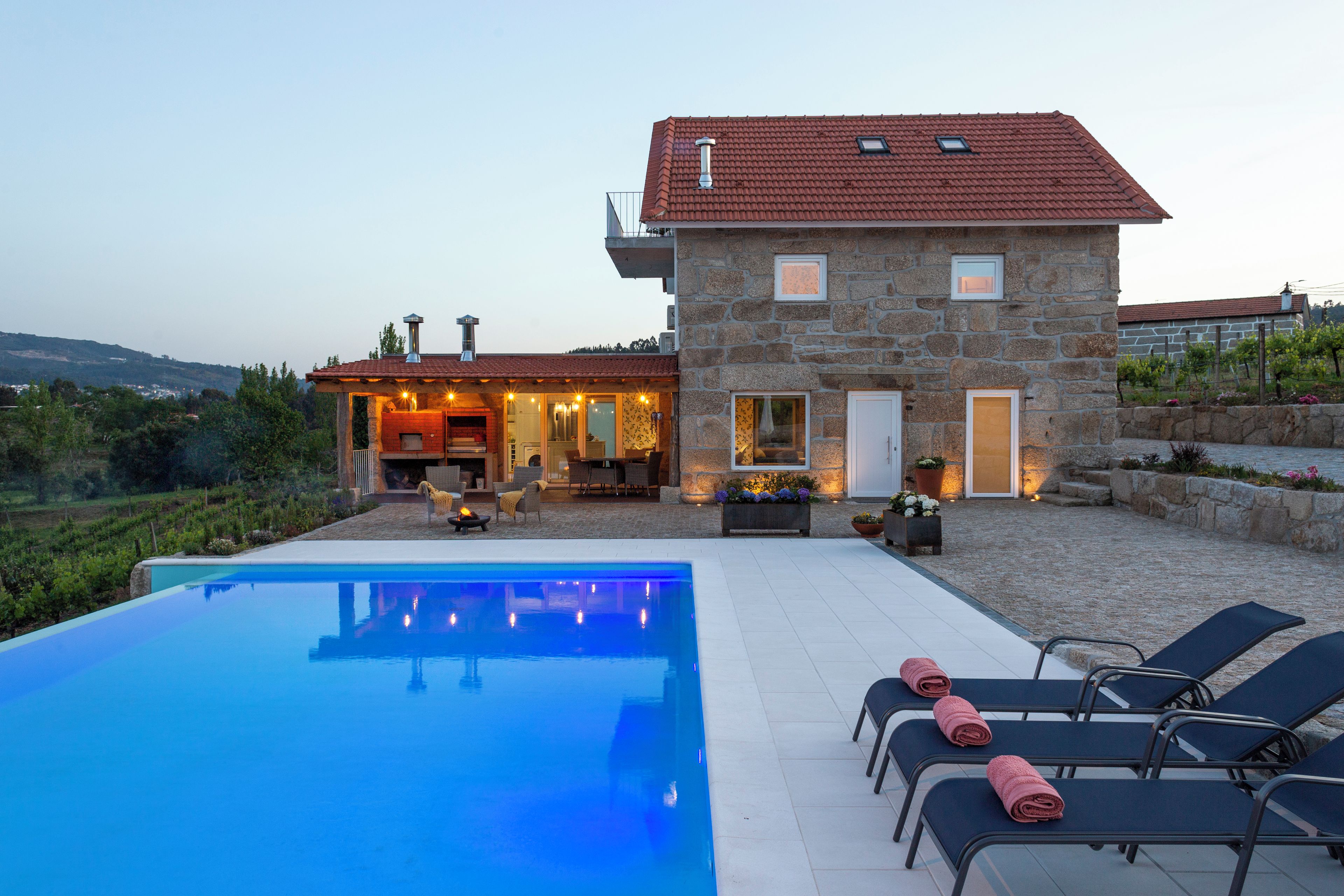 Un edificio de piedra con piscina, mobiliario exterior y vistas al campo.