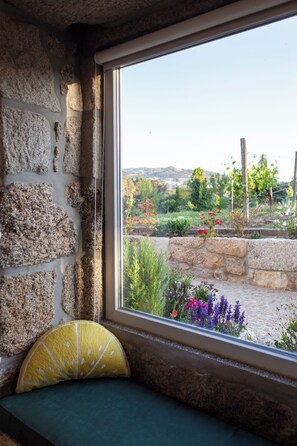 A stone wall with a window overlooking a garden.