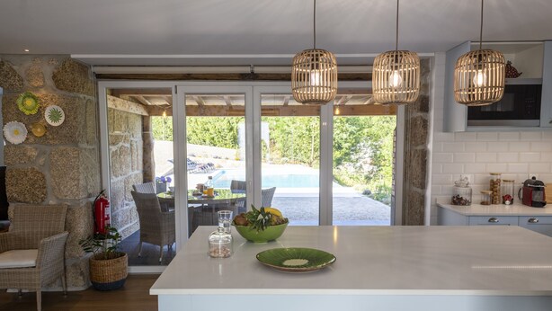 Una cocina moderna con una isla grande, lámparas colgantes de mimbre y vistas al exterior.