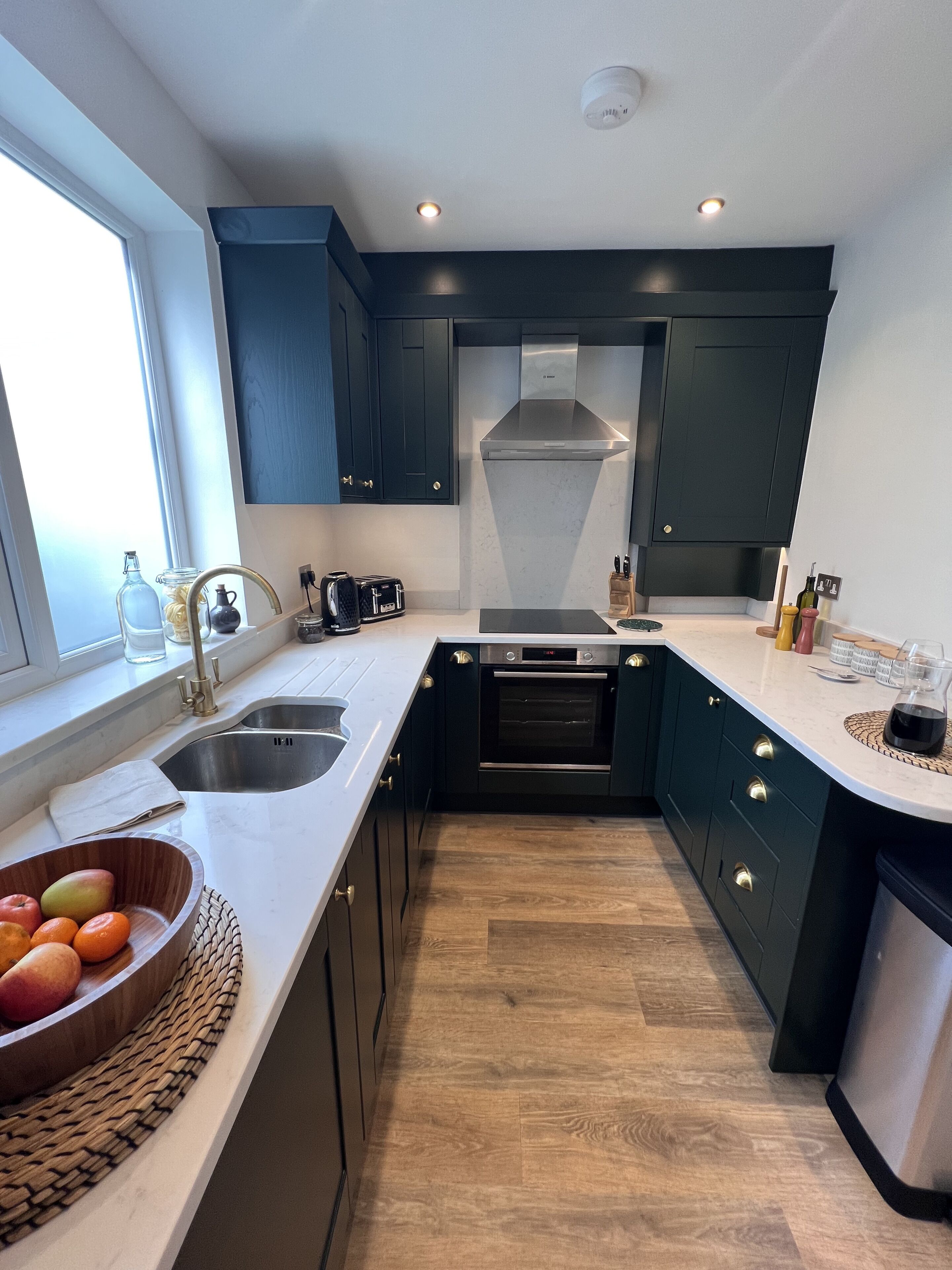 Een moderne keuken met donkere kastjes, een roestvrijstalen spoelbak en een ingebouwde oven.