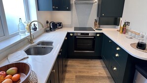 Ett modernt kök med mörka skåp, en diskho i rostfritt stål och en inbyggd ugn.