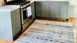 Une cuisine moderne avec des meubles gris, une cuisinière en acier inoxydable et un plan de travail en marbre.