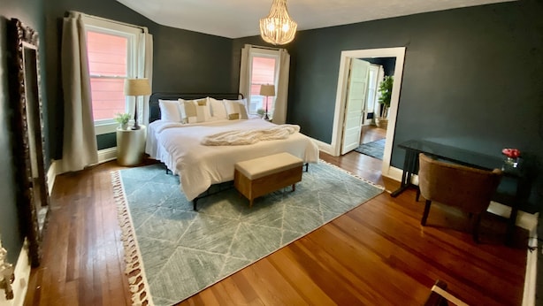 Une chambre à coucher avec un grand lit, des lampes de chevet, un tapis, une chaise et un miroir.