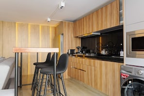 Een moderne keuken met houten kastjes, een inbouwoven en een wasmachine.