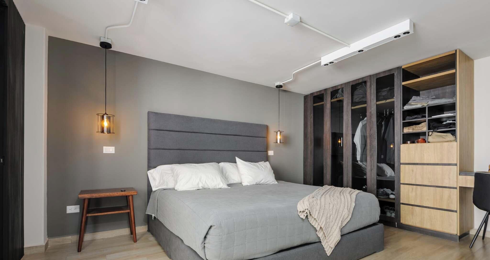 A modern bedroom with a bed, bedside table, wardrobe, and built-in closet.