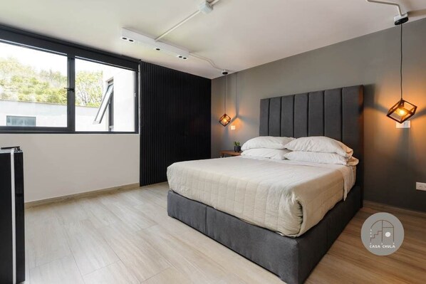 Ein modernes Schlafzimmer mit einem großen Bett, einem Fenster und zwei Wandleuchten.