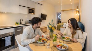Een moderne keuken met inbouwapparatuur, een eettafel met een maaltijd erop en een zithoek met een televisie.