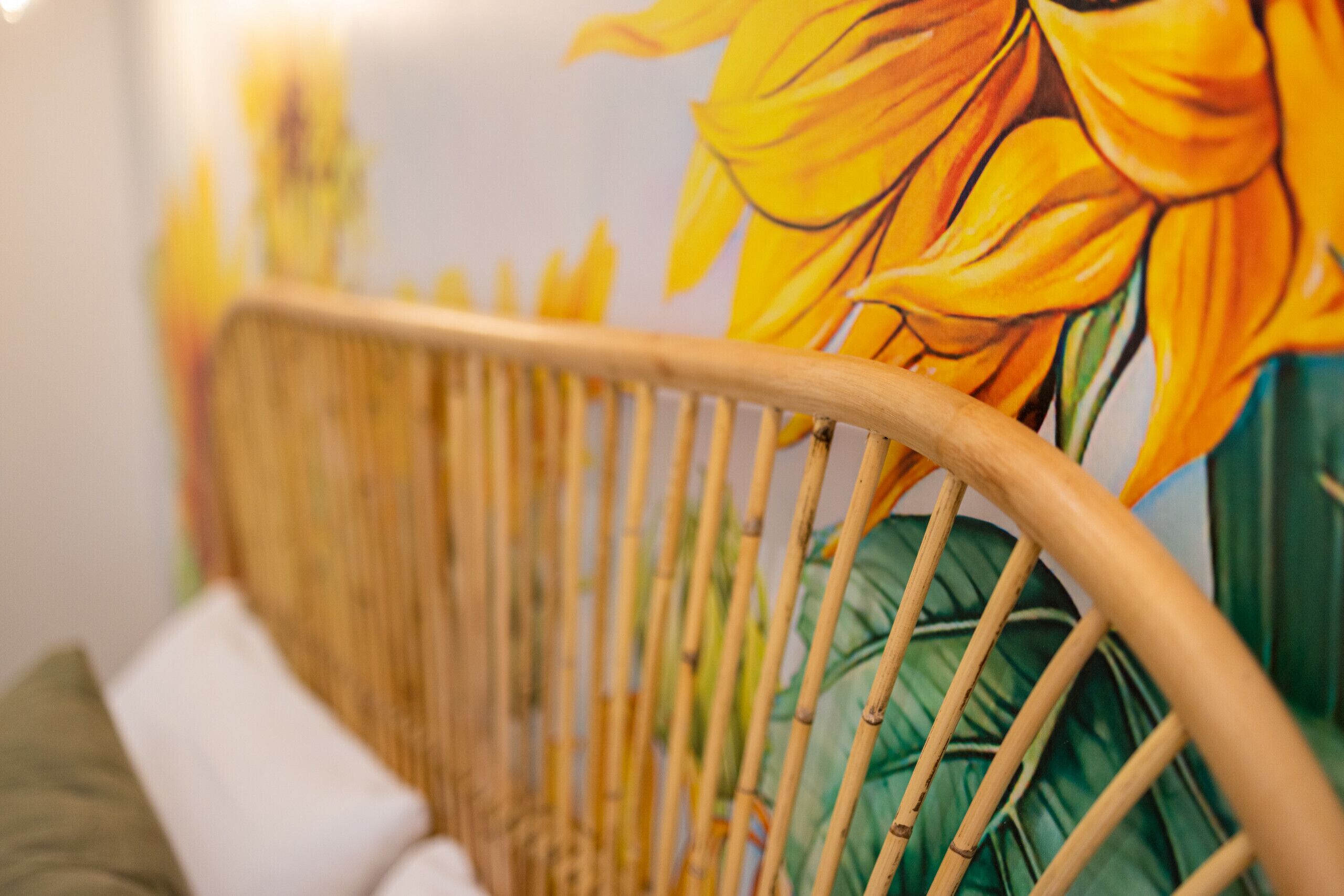A wicker chair with a green cushion and a white pillow.