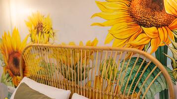 Una habitación con una cama, cabecero de mimbre y un mural de girasoles en la pared.