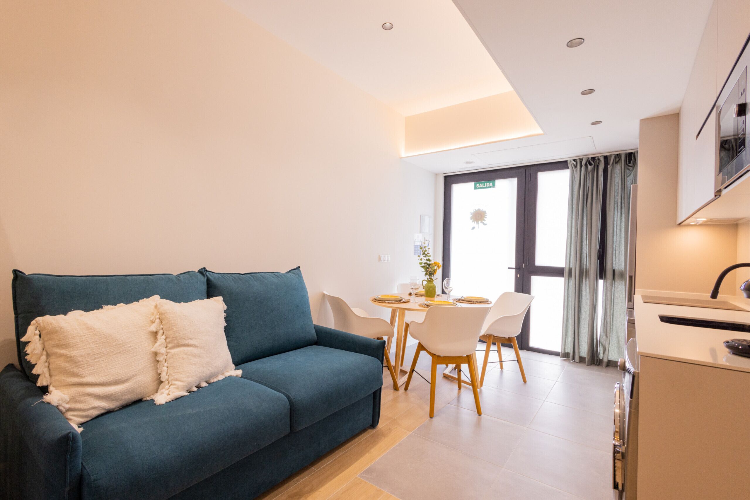Uma sala de estar moderna com um sofá azul e um espaço de jantar com mesa e cadeiras.