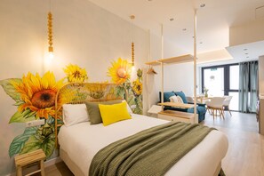 Ein modernes Hotelzimmer mit einem großen Bett, einem Essbereich und Blick auf die Stadt.