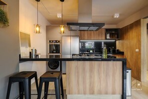 A modern kitchen with a central island, bar stools, and pendant lighting.