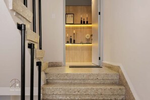 Una escalera conduce a un interior de madera con un diseño moderno, que incluye una repisa con velas y un cuadro enmarcado.