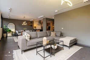 Una sala de estar moderna con un sofá seccional, una mesa de centro de vidrio y un comedor con sillas.