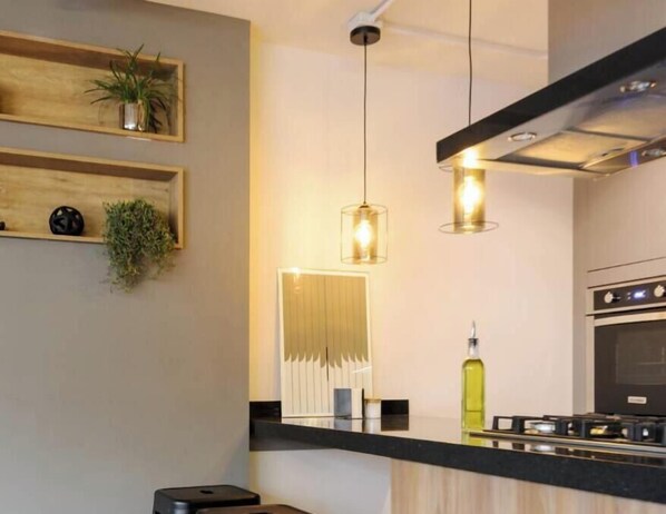 A modern kitchen with wooden shelves, pendant lights, and a gas stove. - Stuning New Luxury Apartment Inside Center Condesa (Ciudad de México)