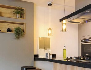 Una cocina moderna con estantes de madera, luces colgantes y una estufa a gas.