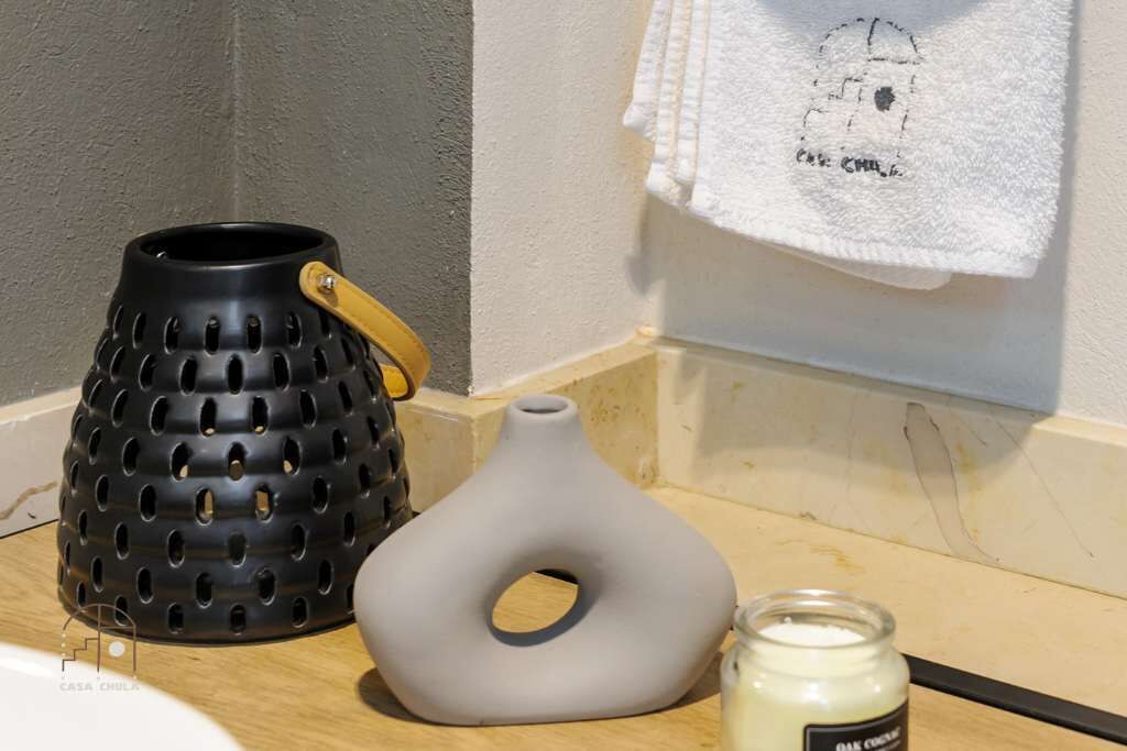 A kitchen counter with a black perforated pot, a gray pot, and a jar of cream.