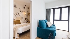A modern bedroom with a bed, a blue sofa, and a large window. - Turia Park Loft IV | 4 Guests | AC and WiFi | Near ZOO (Valencia)