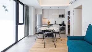 A modern kitchen with a round dining table, black chairs, and a blue sofa. - Turia Park Loft IV | 4 Guests | AC and WiFi | Near ZOO (Valencia)