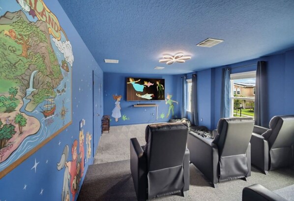 A room with a large wall map, a flat-screen TV, and three reclining chairs.