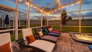 Een terras buiten met lounge stoelen en een jacuzzi.