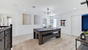 A spacious room with a dark wooden table, a bench, and a ceiling light fixture. - Super 8BR Resort Pool Vacation Home Near Disney (Davenport)