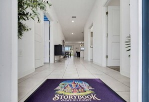 Een gang met een paars tapijt, het logo van Storybook Vacation Homes, witte wanden en een deur aan het einde.