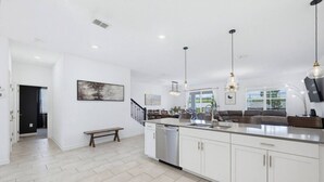 A modern kitchen with a central island, white cabinetry, and pendant lighting. - Super 8BR Resort Pool Vacation Home Near Disney (Davenport)