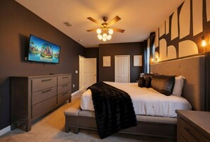 Une chambre à coucher comprenant un lit, une commode, un téléviseur et un ventilateur de plafond.