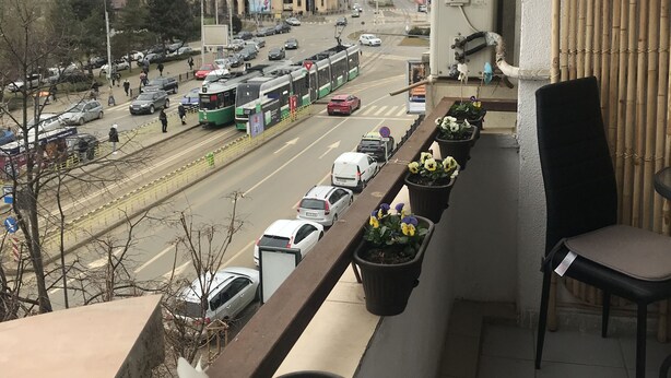 A balcony with a view of a city street, a tram, and a large building with a dome.