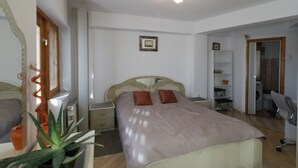A bedroom with a bed, bedside tables, a wardrobe, a mirror, and a ceiling light fixture.