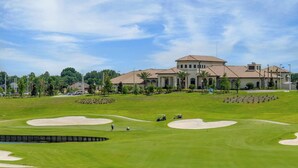 Ein Golfplatz mit Sandbunkern, einem Clubhaus und Palmen.