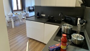 A modern kitchen with a black countertop, a sink, and a stove. There is a dining area with a table and chairs visible in the background. - Blue Lake apartment with pool and lake view (Stresa)
