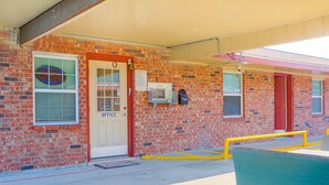 A brick building with a red door labeled "OFFICE," a neon sign, and a yellow ramp leading to the entrance. - Economy Inn By OYO Lockport near Houma (Lockport)