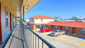 A hotel with a red-roofed building, a parking lot with two cars, and a clear blue sky. - Economy Inn By OYO Lockport near Houma (Lockport)