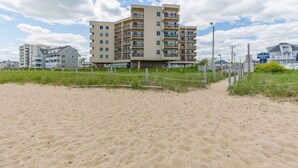 A beachfront hotel with multiple floors, a sandy beach in the foreground, and a clear sky. - Seawatch Oceanfront Unit 602 (Old Orchard Beach)
