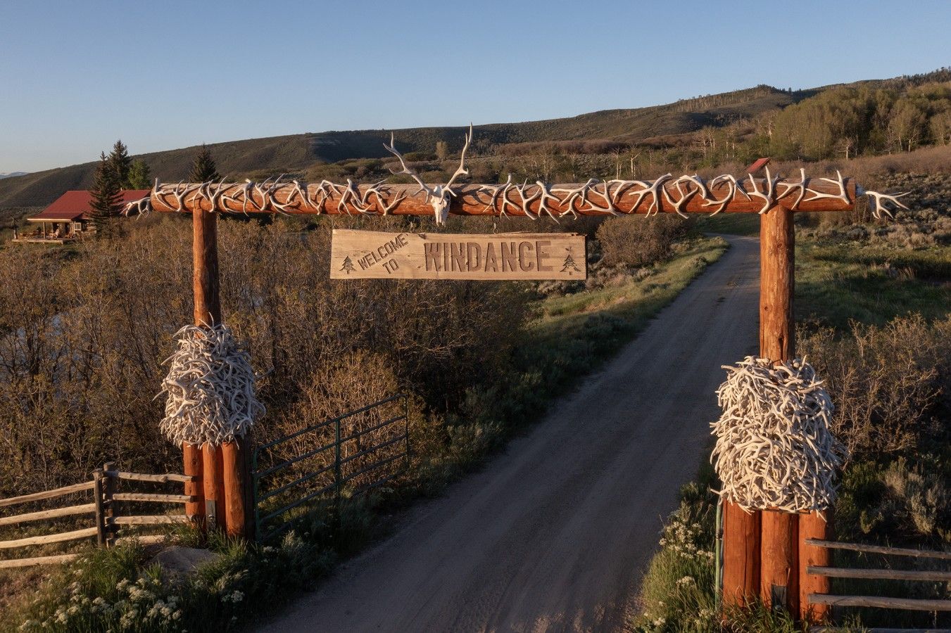 A wooden sign with antlers and the words 'WELCOME TO WINDANCE' on a rural road.