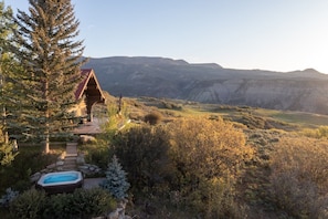A log cabin with a hot tub and a scenic mountain view.