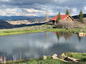 Une cabane au toit rouge surplombant un lac paisible, entouré de montagnes.