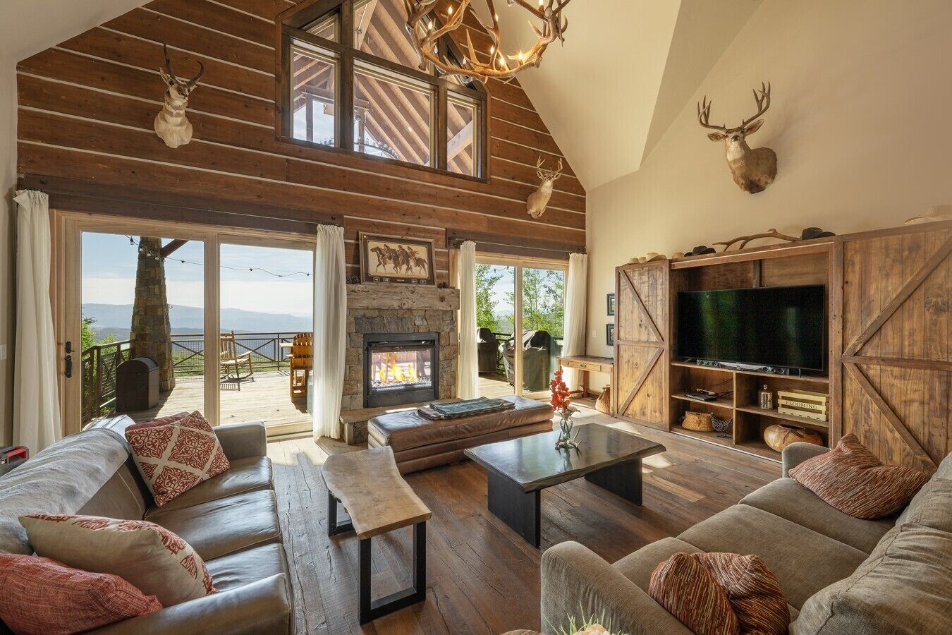 A spacious living room with a fireplace, large windows, and a television.