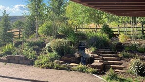 Un cadre extérieur rustique agrémenté d’un pont en bois, d’une petite cascade et d’un sentier en pierre.