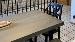 Un espace repas avec une table et des chaises en bois, un mur en pierre et des ampoules suspendues.