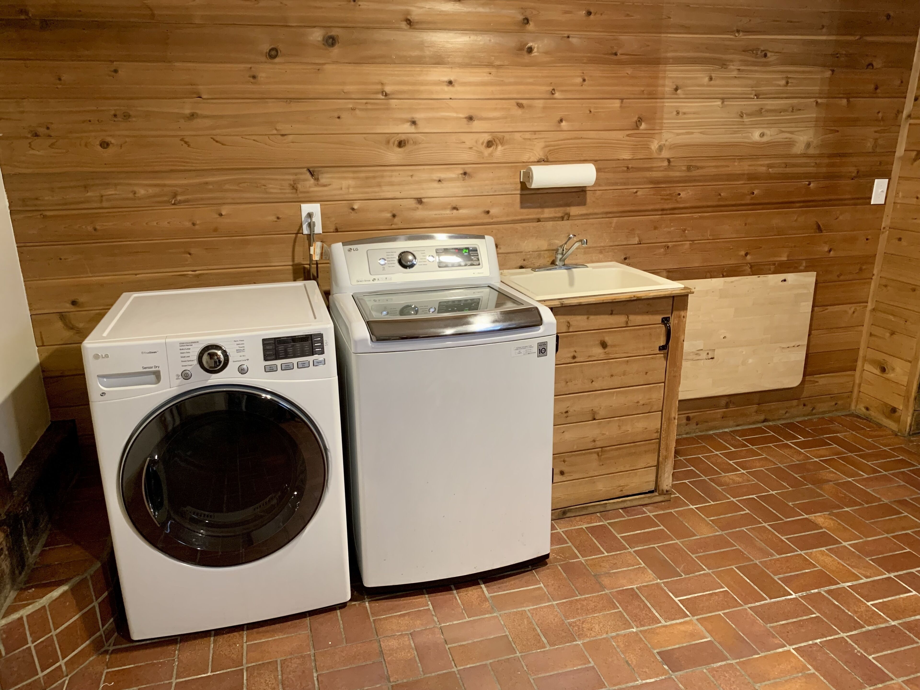 Een wasserette met twee wasmachines, een wasbak en houten wanden.