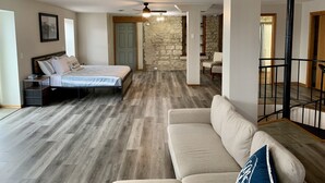 Une chambre spacieuse avec un lit, des tables de chevet et un mur en pierre.
