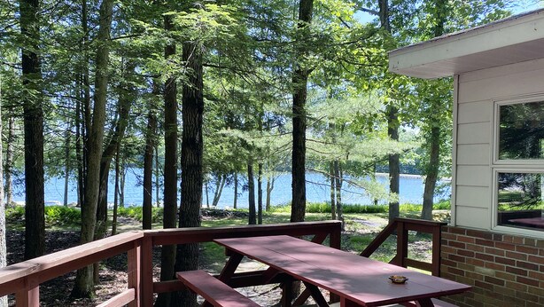 Eine Holzterrasse mit Picknicktischen mit Blick auf einen See.
