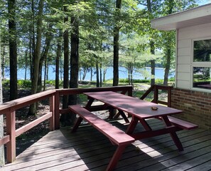A wooden deck with picnic tables overlooking a lake. - Charming Lake Front Cabin in the Poconos (Stroudsburg)