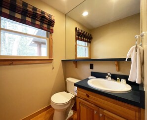 A bathroom with a toilet, sink, and mirror. - Charming Lake Front Cabin in the Poconos (Stroudsburg)